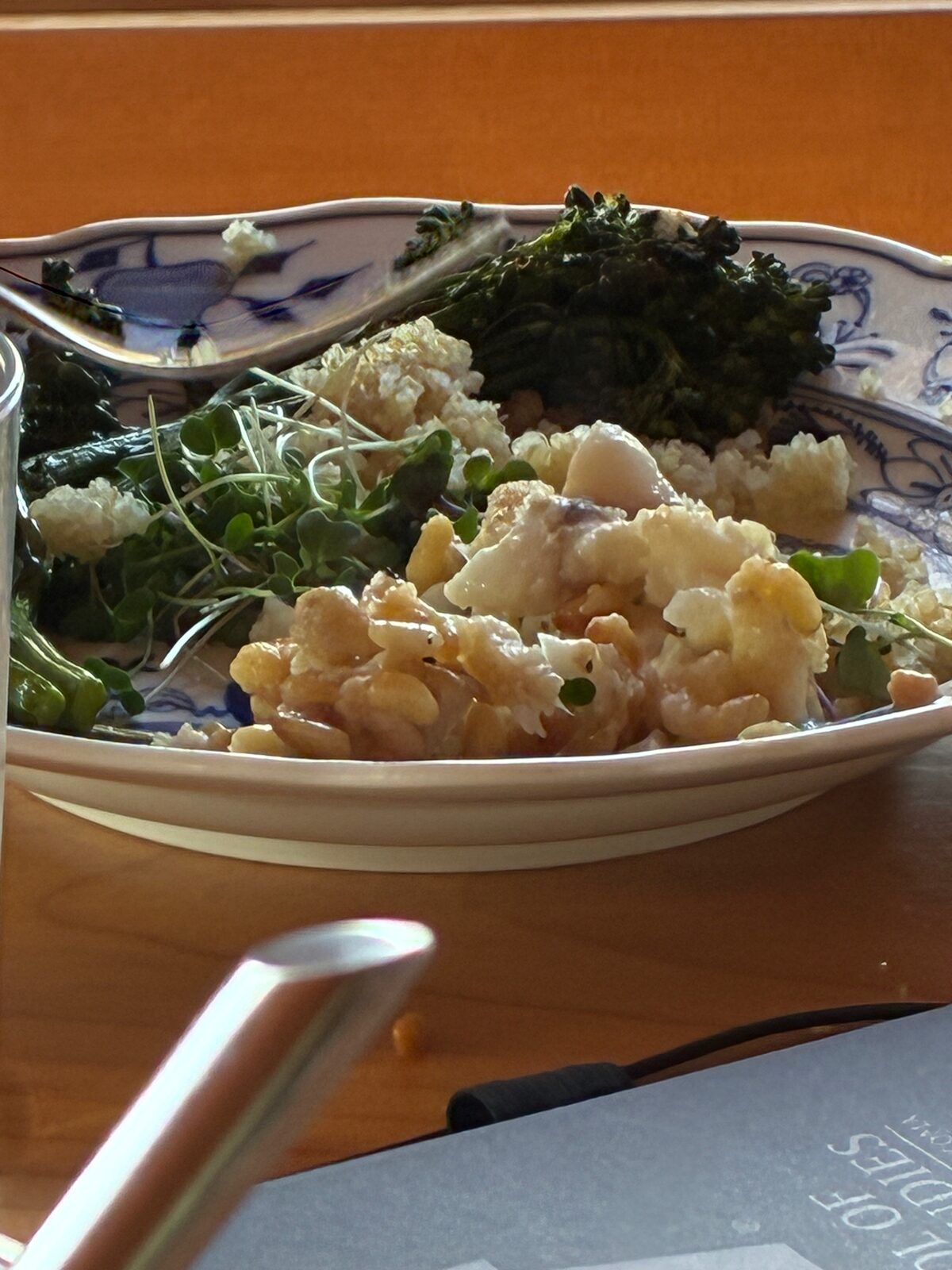 A serving dish of grains, cauliflower and roasted broccolini garnished with bright pea-shoot microgreens.